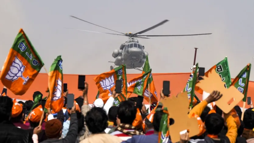 Supporters wave BJPs flags at Prime Minister Narendra Modis helicopter, during a public meeting ahead of the Delhi Assembly elections, at Kartar Nagar in New Delhi. 