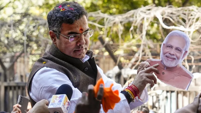 BJP candidate from New Delhi assembly constituency Parvesh Verma holds a portrait of Prime Minister Narendra Modi amid celebration outside a counting center after claiming victory in the Delhi Assembly polls.