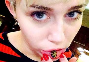 miley cyrus goes funky dons a tattoo on lower lip see pics