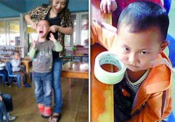 cruel teacher in china holds a screaming child off the ground by his ears